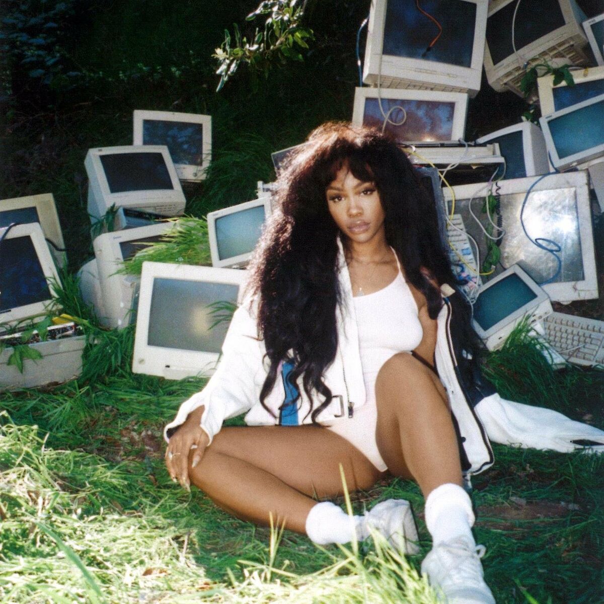 SZA sentada em meio a uma pilha de monitores de computador antigos